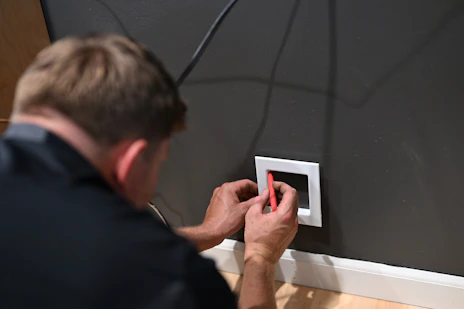 a man fixing a light switch on a wall