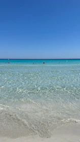 Crystal clear turquoise waters gently lapping a sandy beach in Ayvalik under bright sunlight.