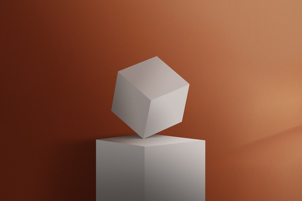 Un cubo bianco seduto sulla cima di un piedistallo bianco