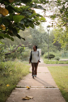 A calm outdoor scene with Luz walking thoughtfully along a sunlit path.