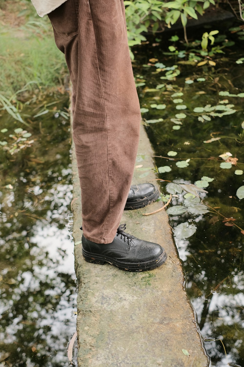 a person standing on a ledge near a body of water