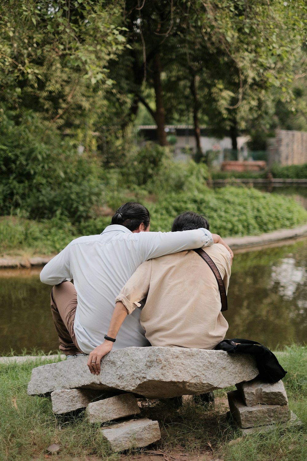 a couple of men sitting on top of a stone bench