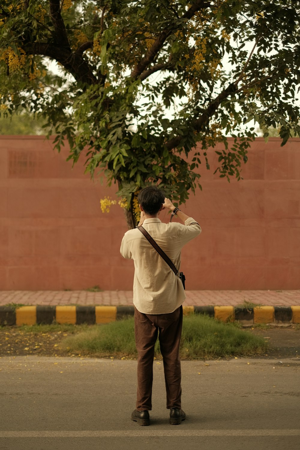 a man standing on the side of a road taking a picture