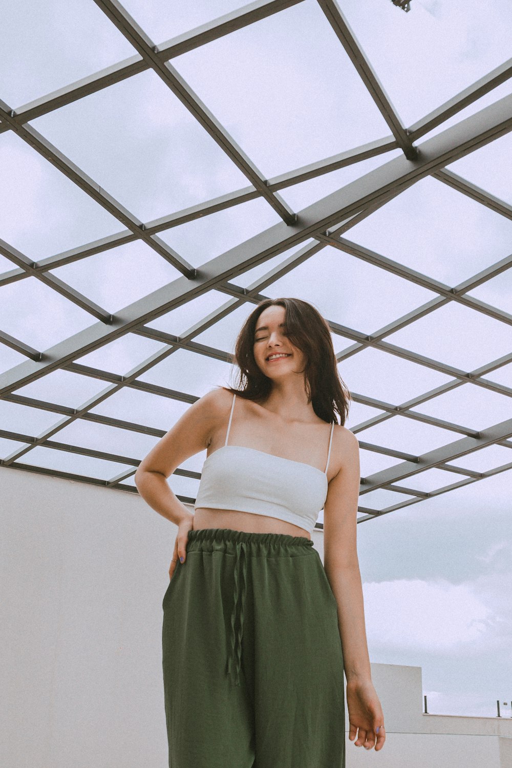 a woman in a white top and green pants