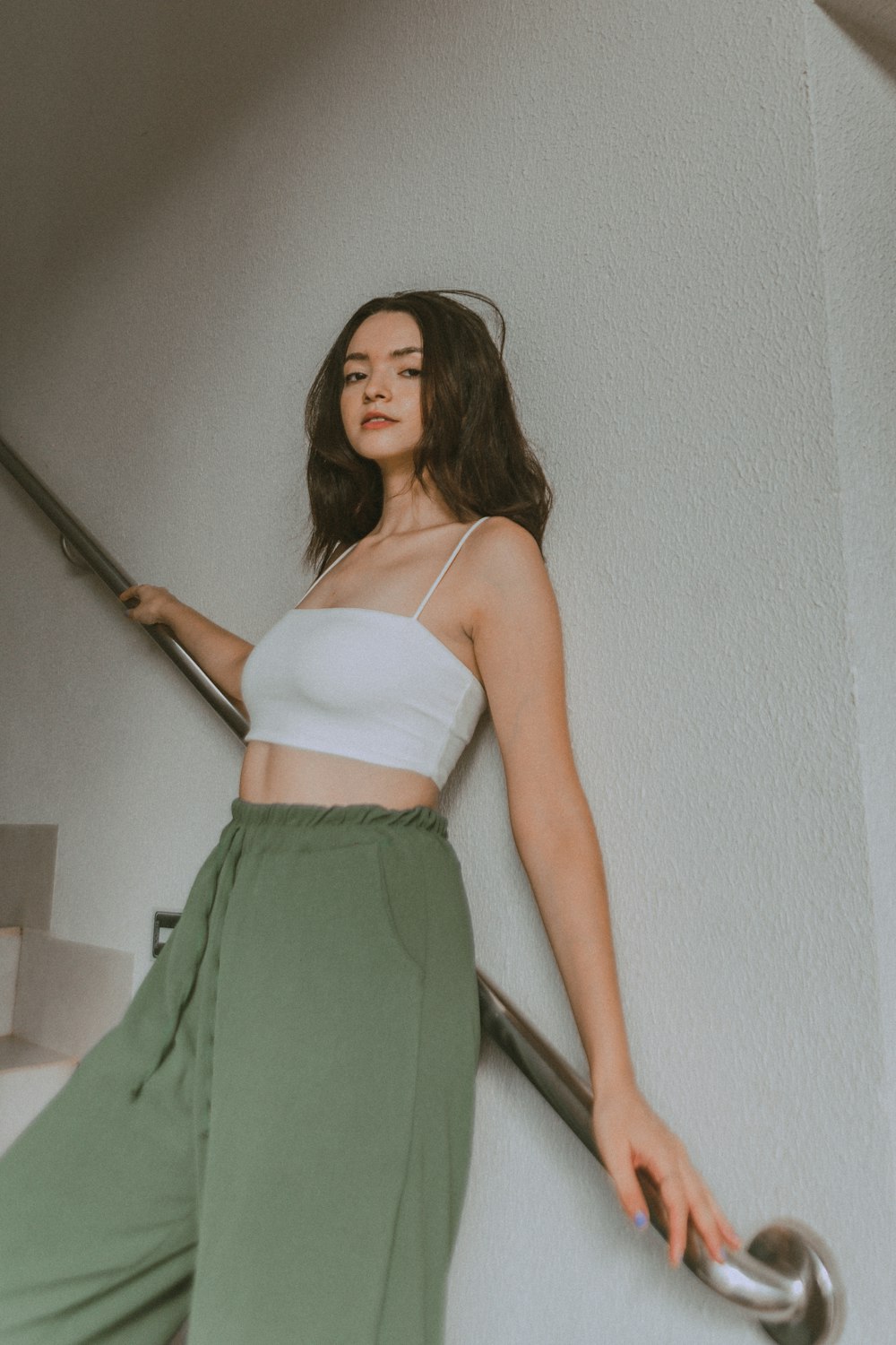 a woman in a white top and green pants