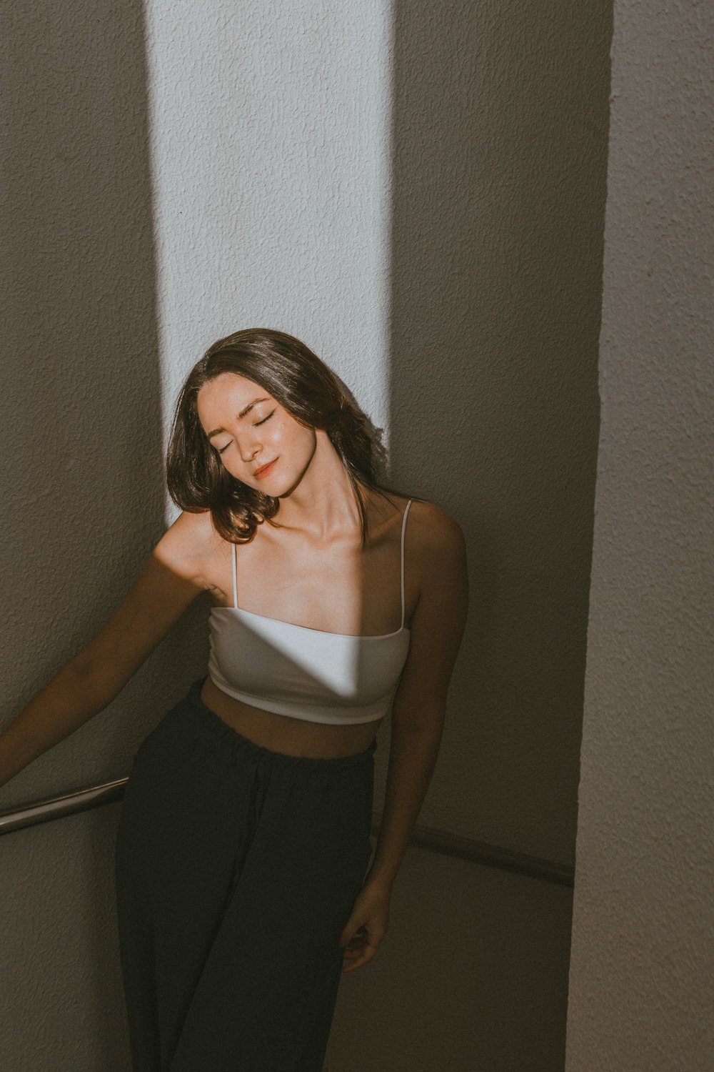 a woman leaning against a wall with her eyes closed