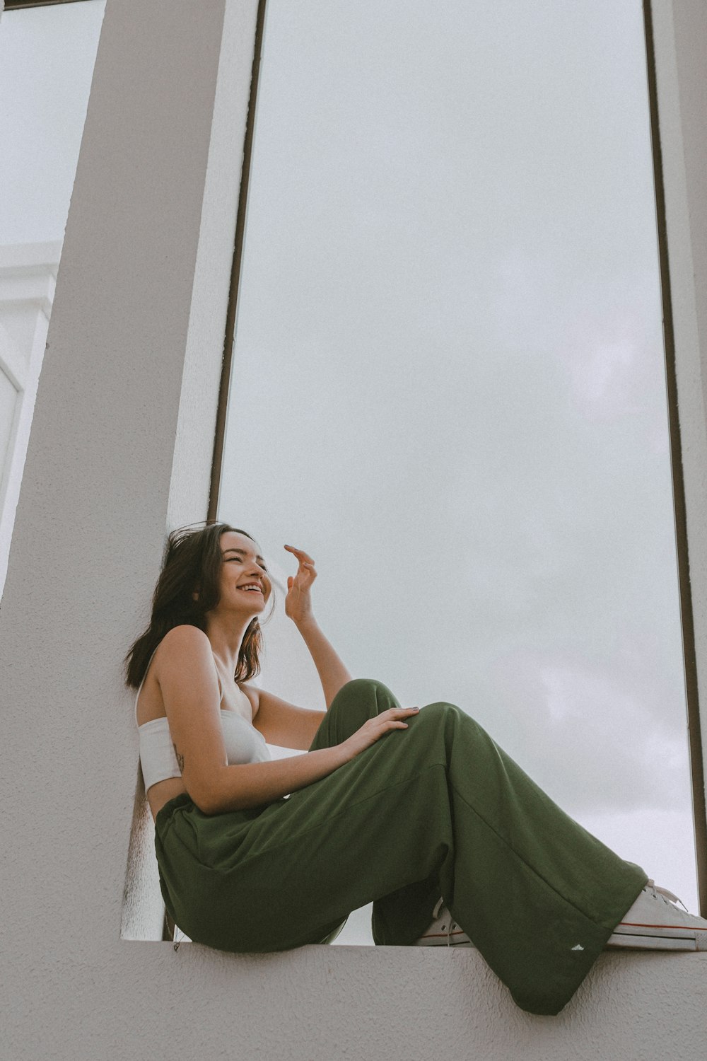 a woman sitting on a window sill smoking a cigarette