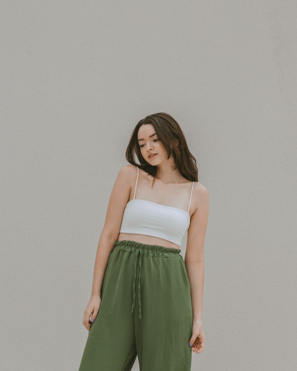a woman in a white top and green pants