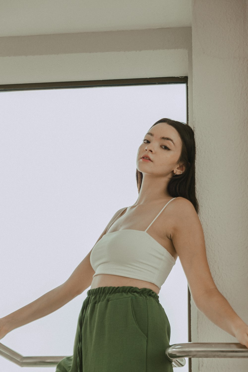 a woman in a white top and green pants