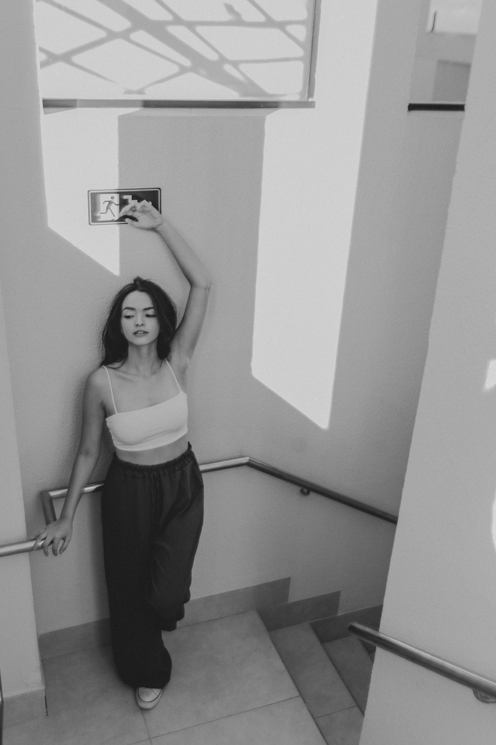 a woman in a tank top is standing in a stairwell