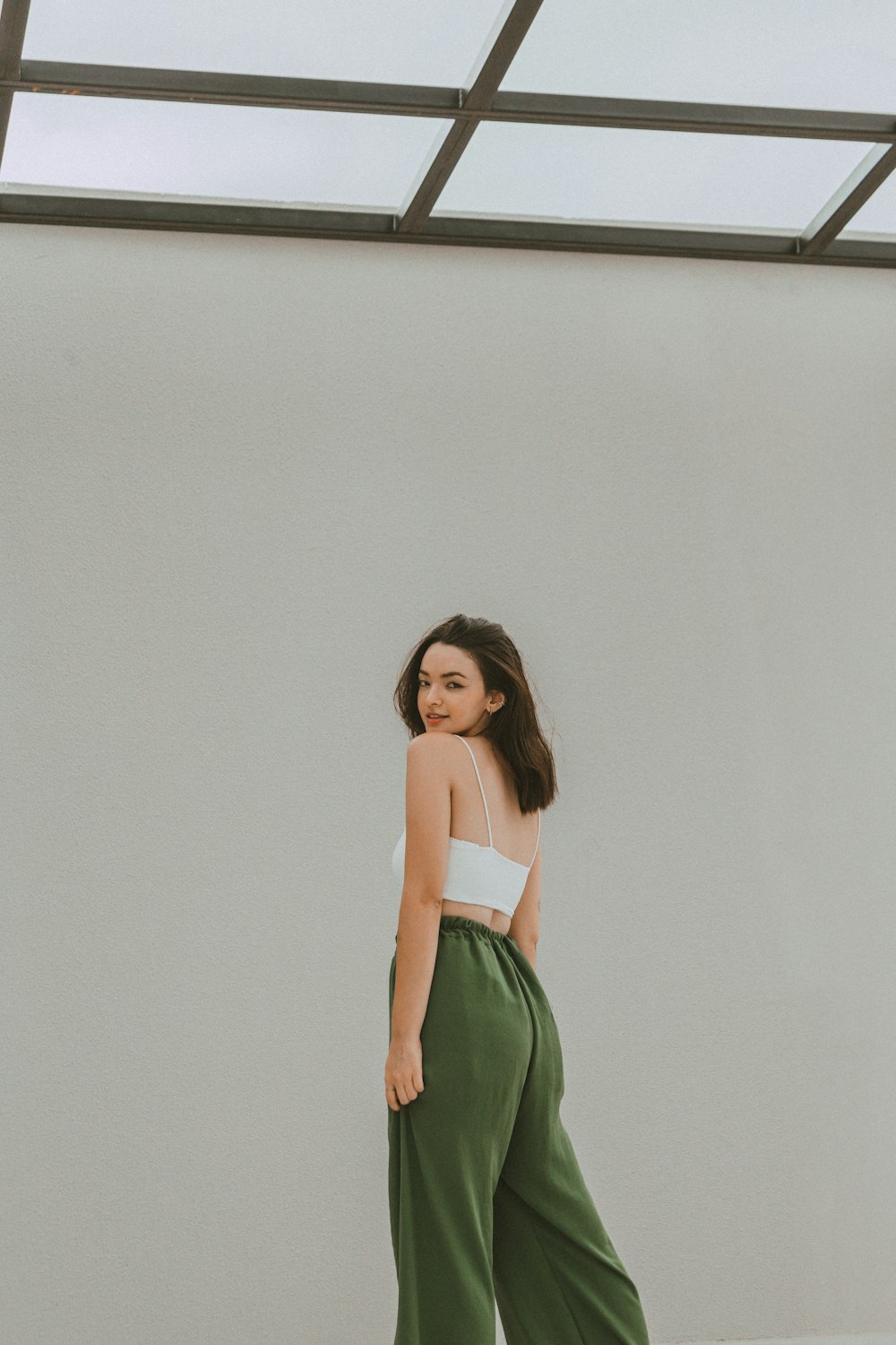 a woman in a white top and green pants