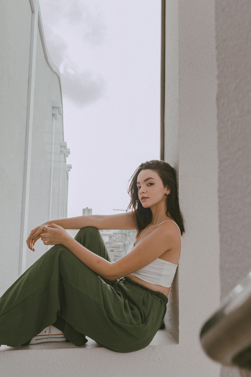 a woman sitting on a window sill with her legs crossed