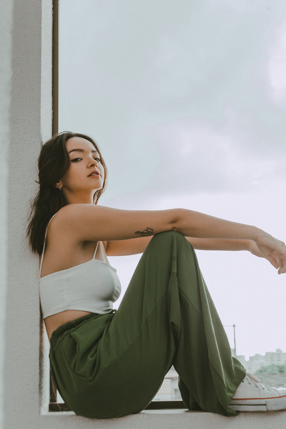 a woman sitting on a window sill with her legs crossed