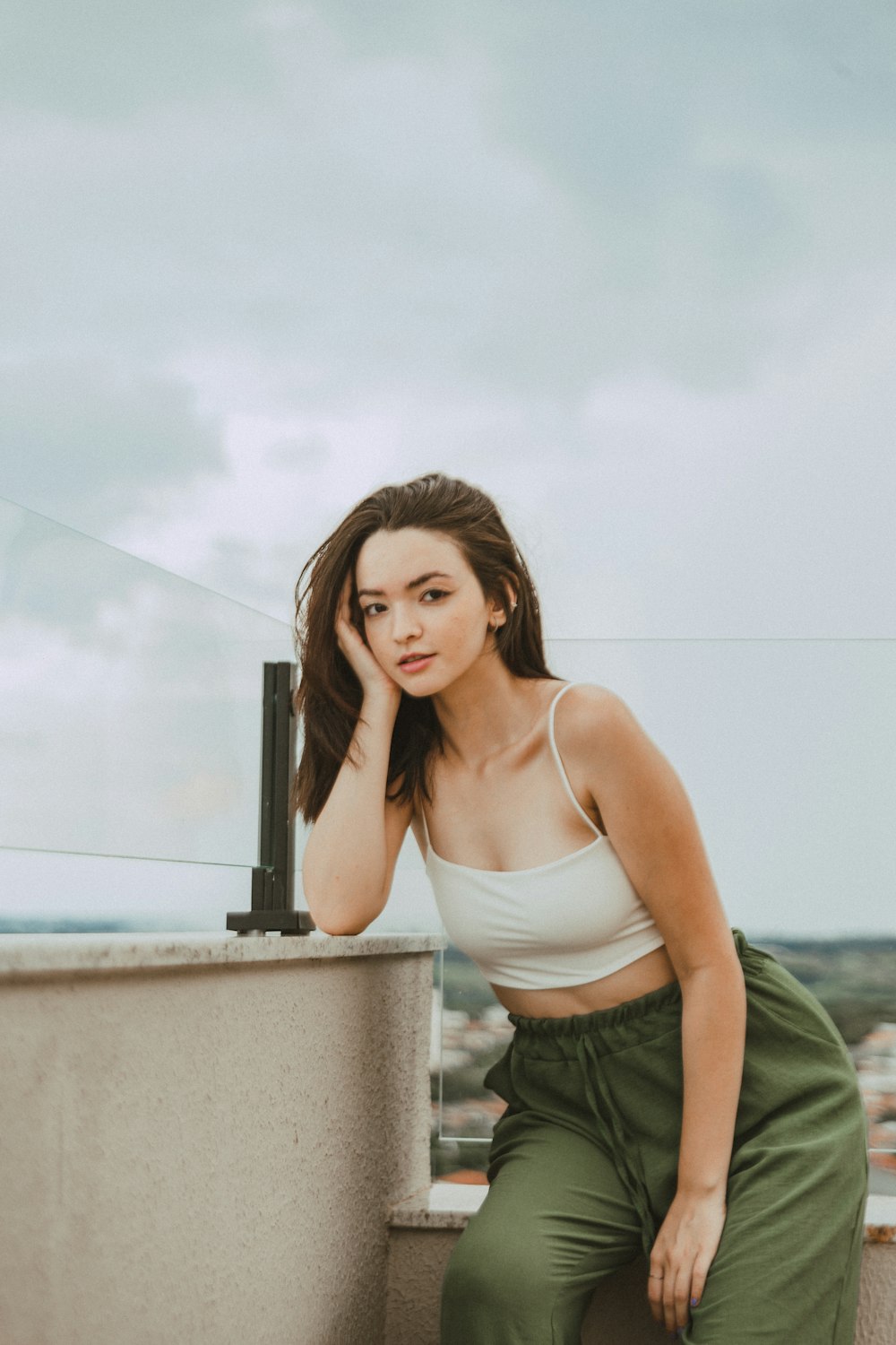 a woman sitting on a ledge with her hand on her head