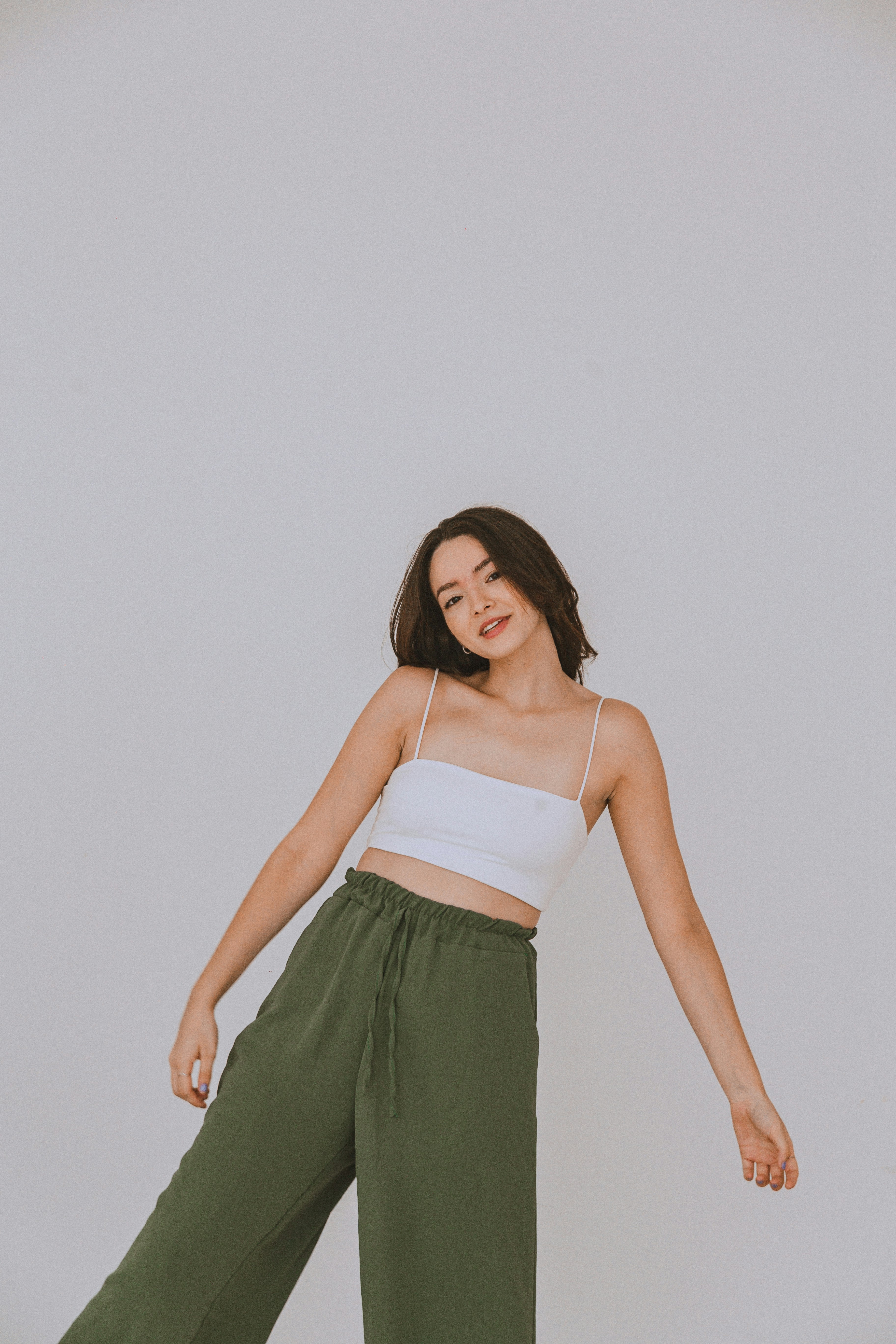 a woman in a white top and green pants