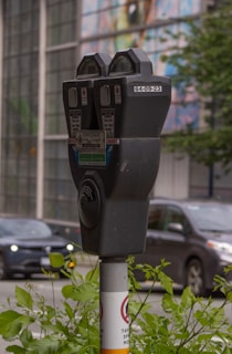 Close-up of a smart parking meter installed on a busy sidewalk.