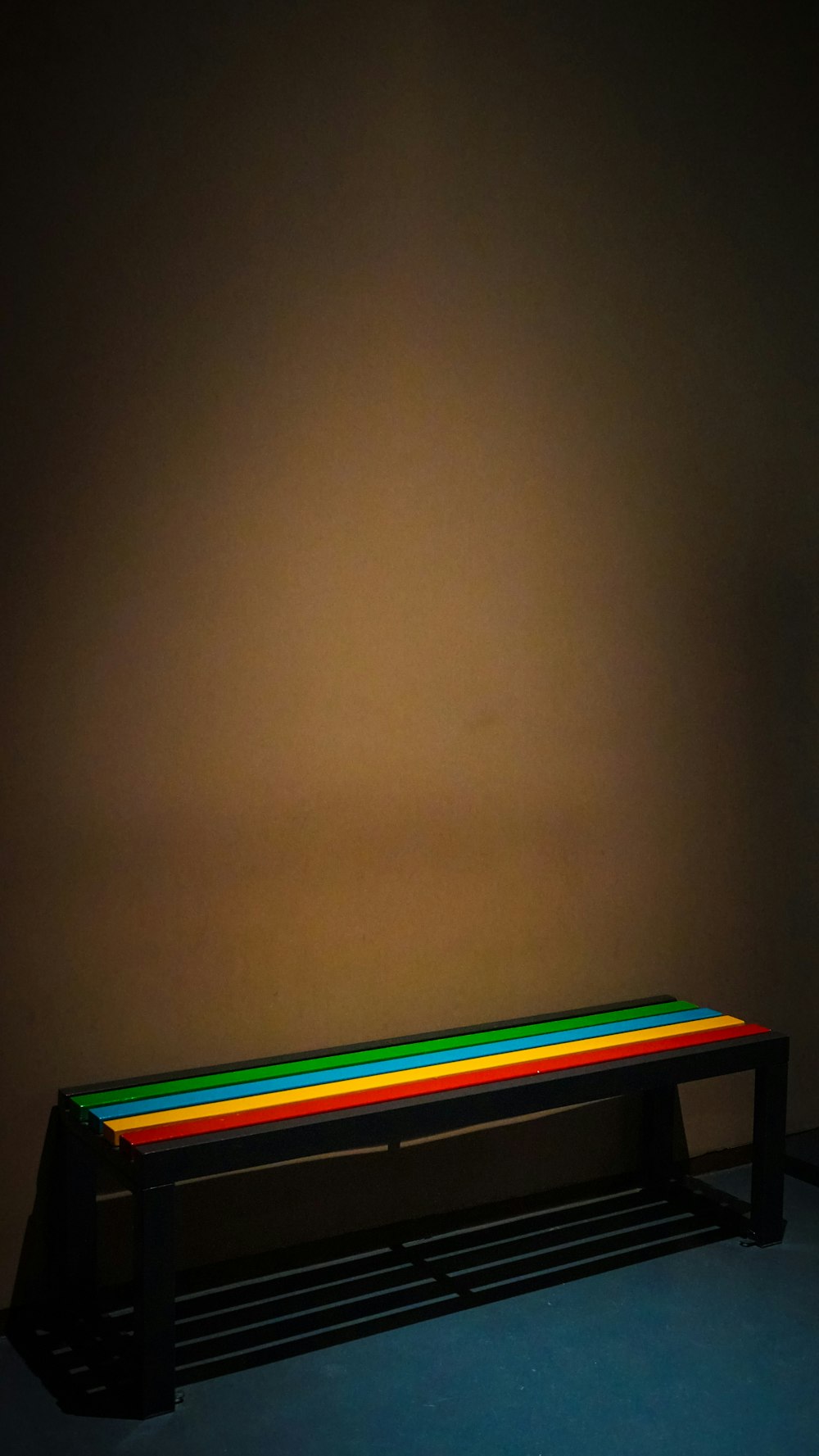 a bench in a dark room with a rainbow light on it
