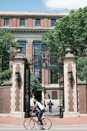 a man riding a bike past a tall building