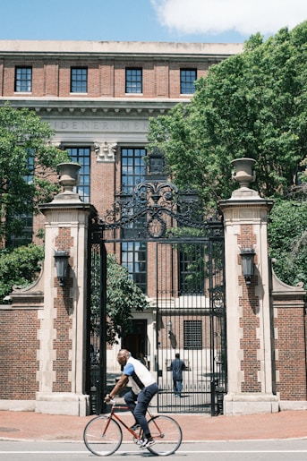 a man riding a bike past a tall building