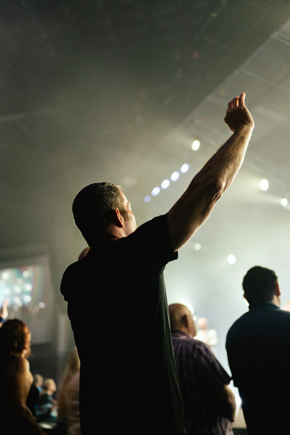 a man raising his arm in the air at a concert
