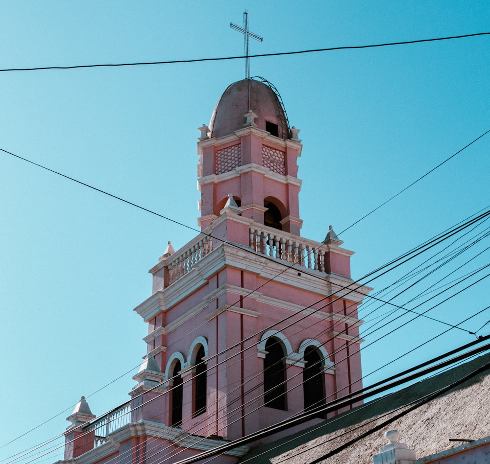 a pink church steeple with a cross on top
