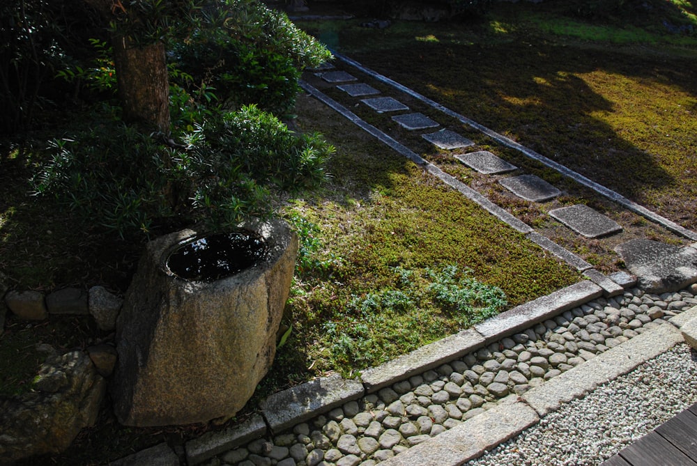 a stone planter sitting on top of a lush green hillside