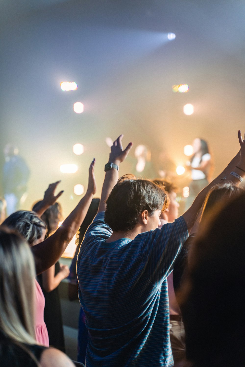 a crowd of people at a concert with their hands in the air