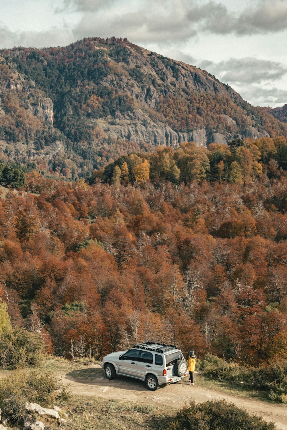 a car parked on a dirt road in front of a mountain