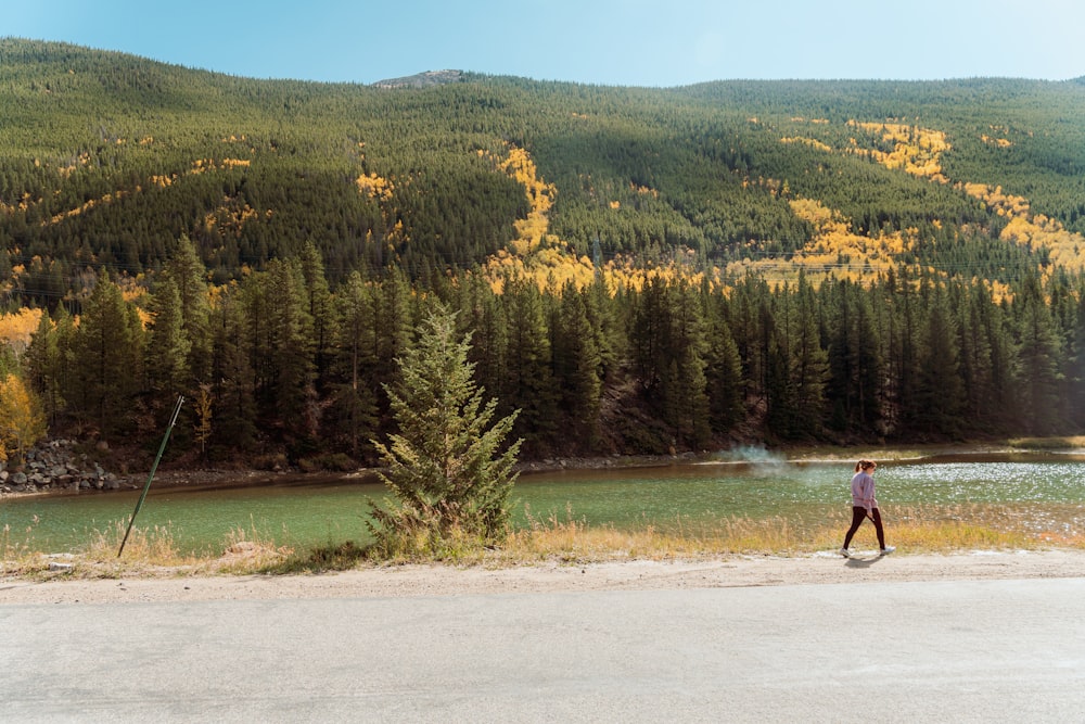 a man walking across a field next to a forest