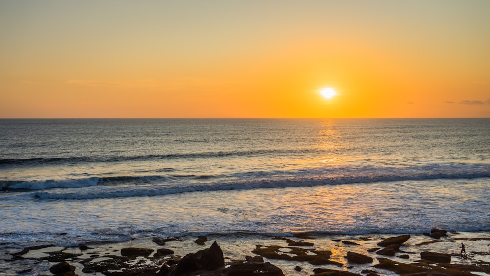 the sun is setting over the ocean on the beach