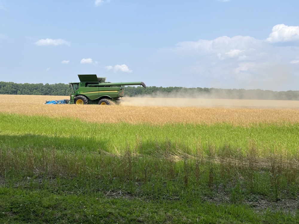 a large green truck driving through a wheat field