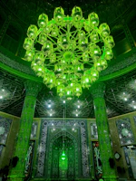 Elegant mosque chandelier glowing warmly against a dark green and gold interior