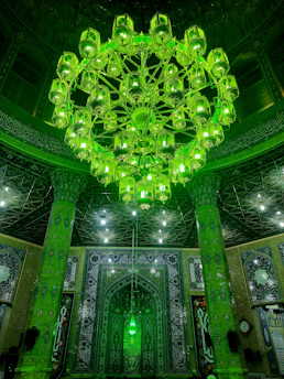 Elegant mosque chandelier glowing warmly against a dark green and gold interior