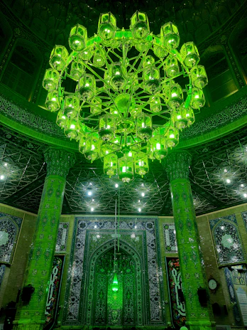 Elegant mosque chandelier glowing warmly against a dark green and gold interior.