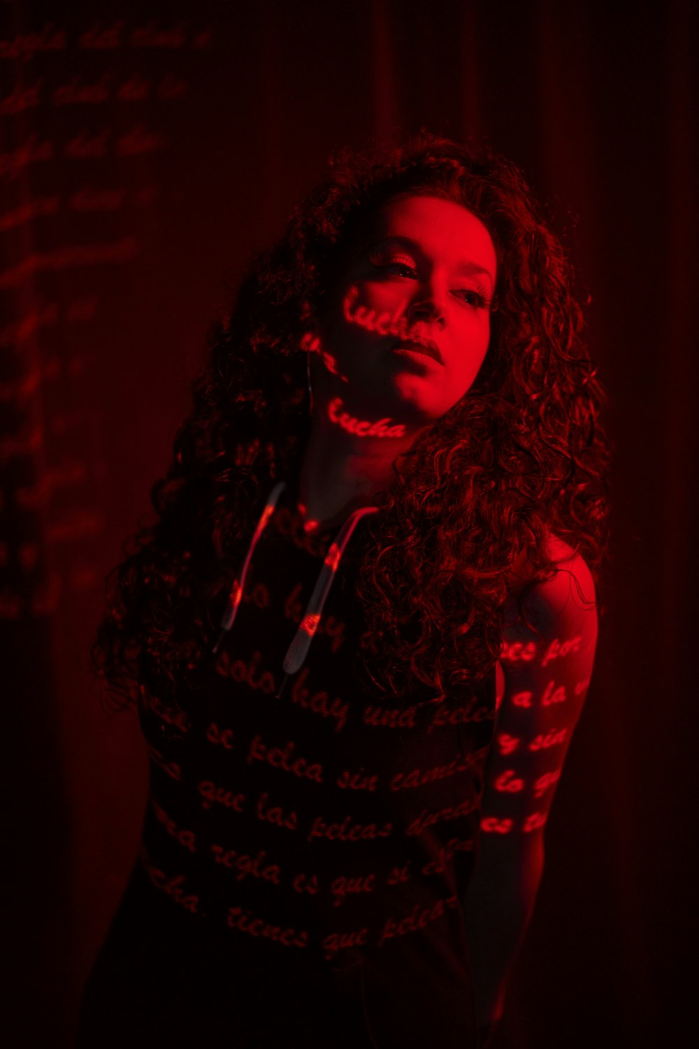 a woman with long curly hair standing in a dark room