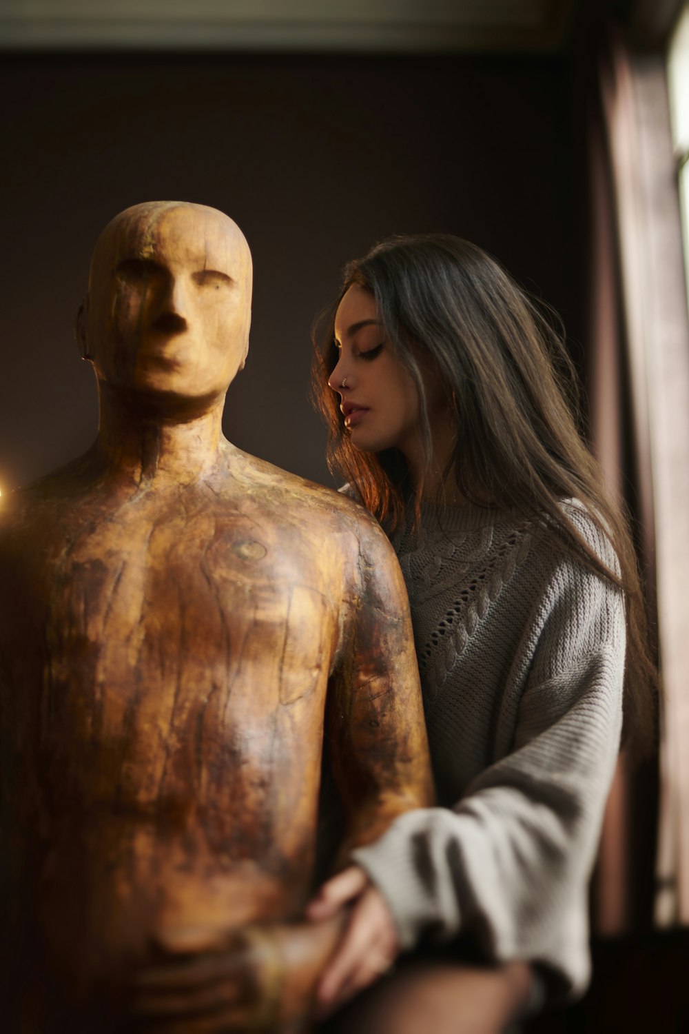 a woman standing next to a wooden statue