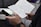 Close-up of hands taking notes during an online class on a laptop.