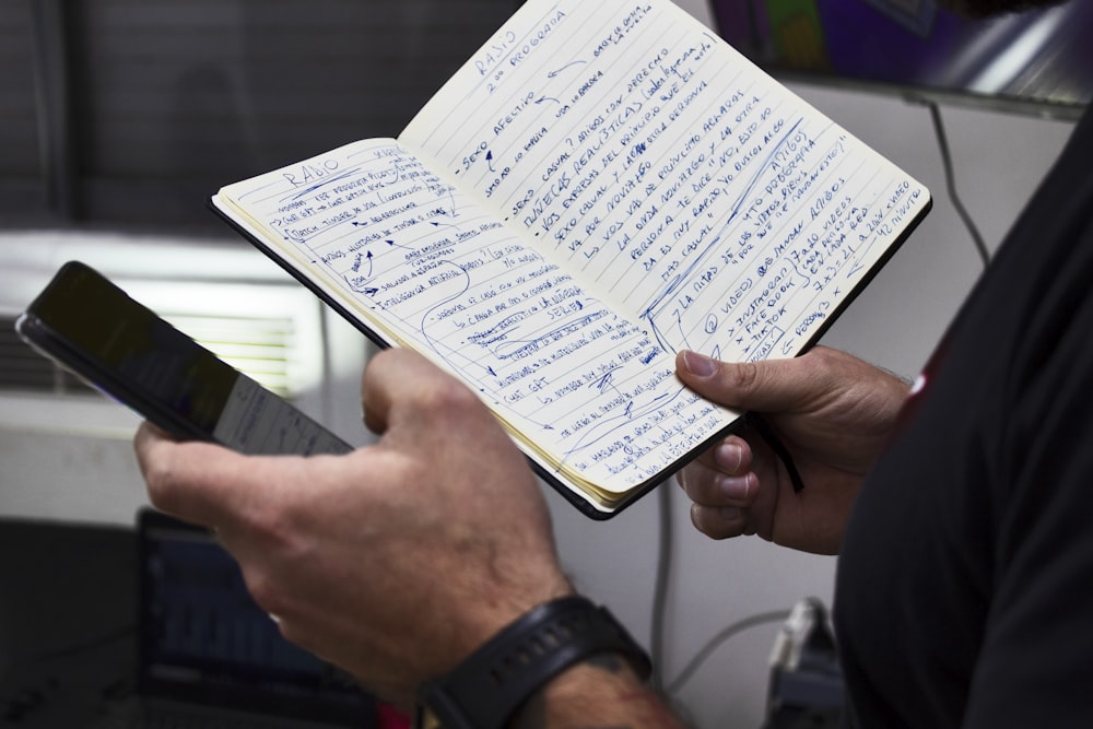 a person holding a book and a cell phone