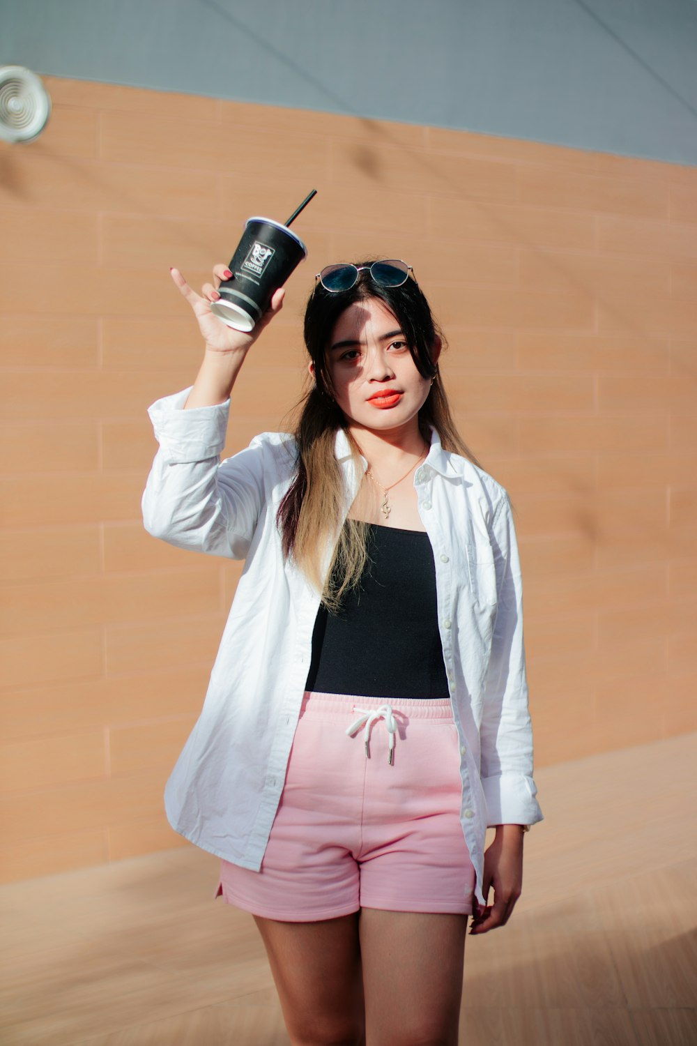 a woman in pink shorts and a white jacket holding a cup
