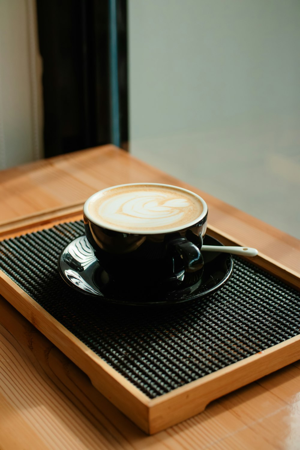 a cup of coffee sitting on top of a wooden tray