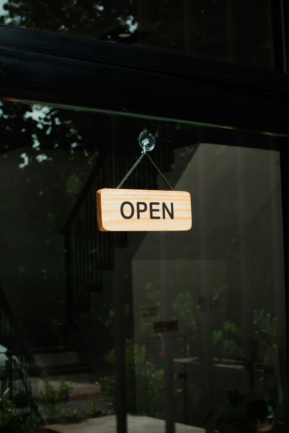 a sign hanging from a glass door that says open