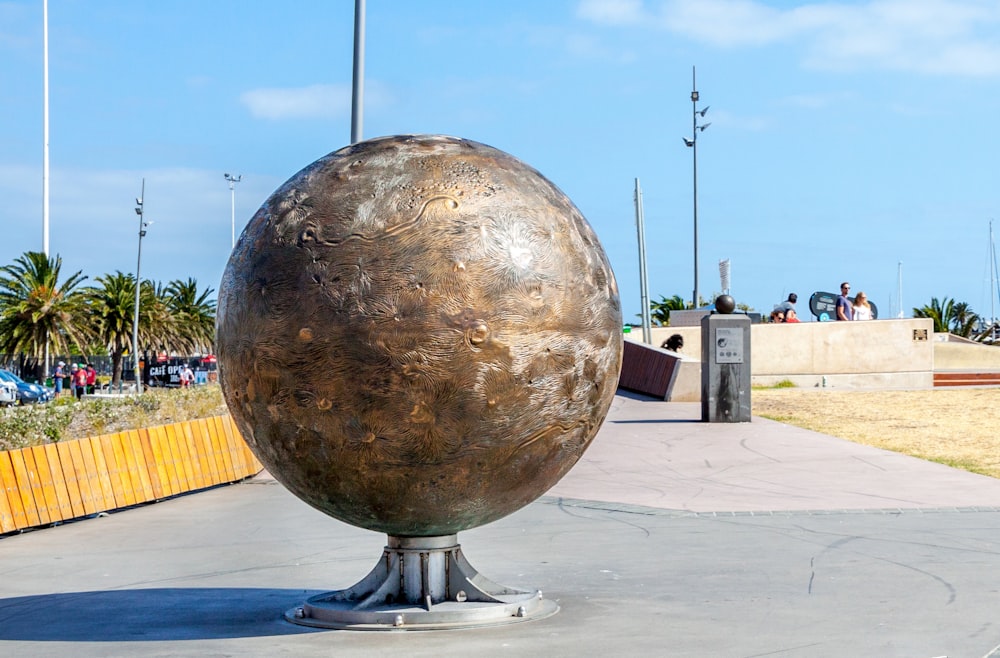 una grande sfera di metallo seduta sopra un terreno di cemento