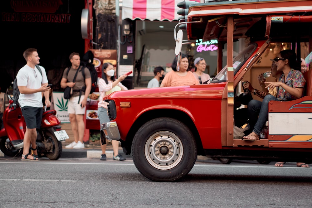 a group of people riding on the back of a red truck