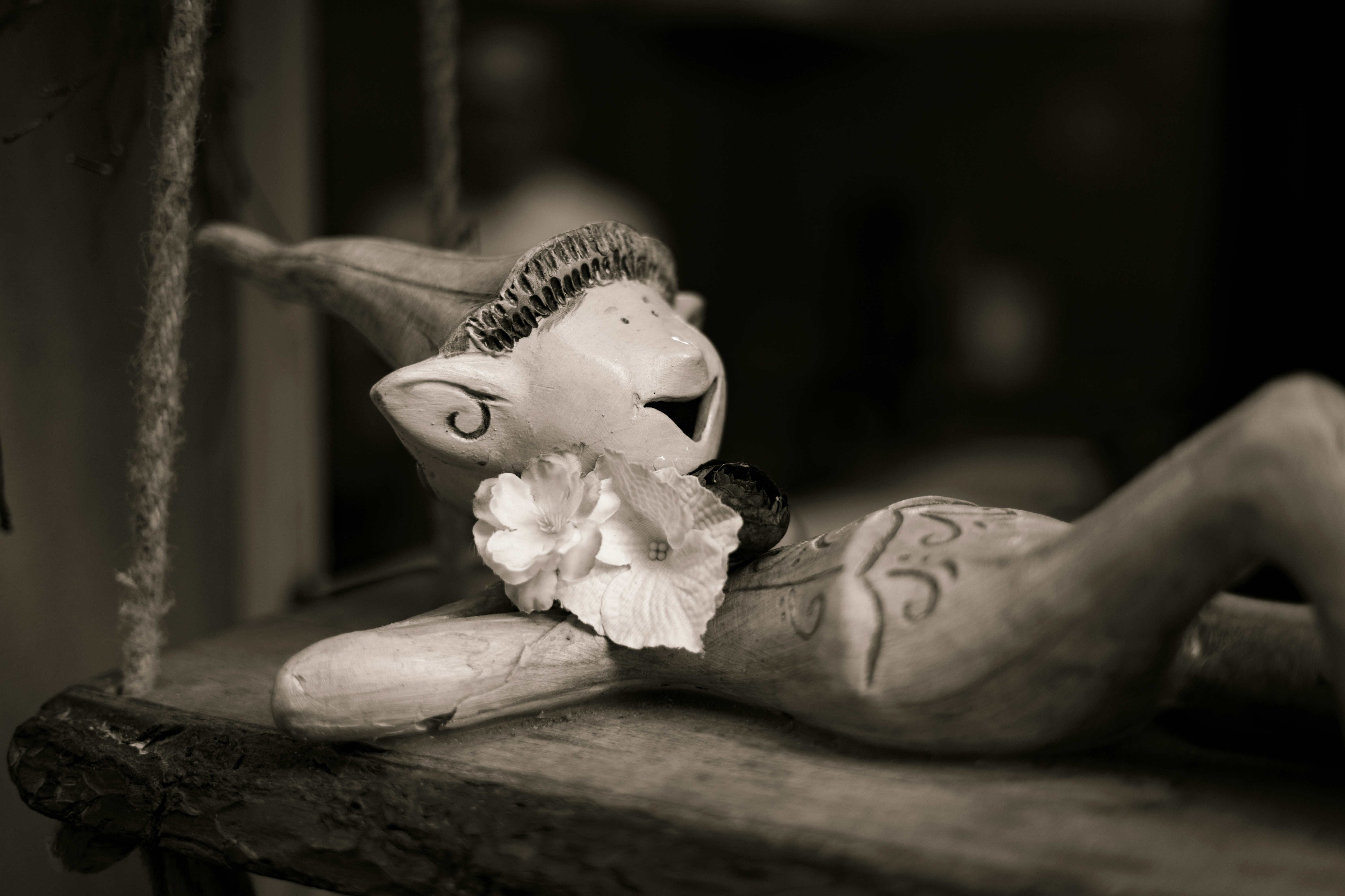 A wooden doll playfully rests on a swing.