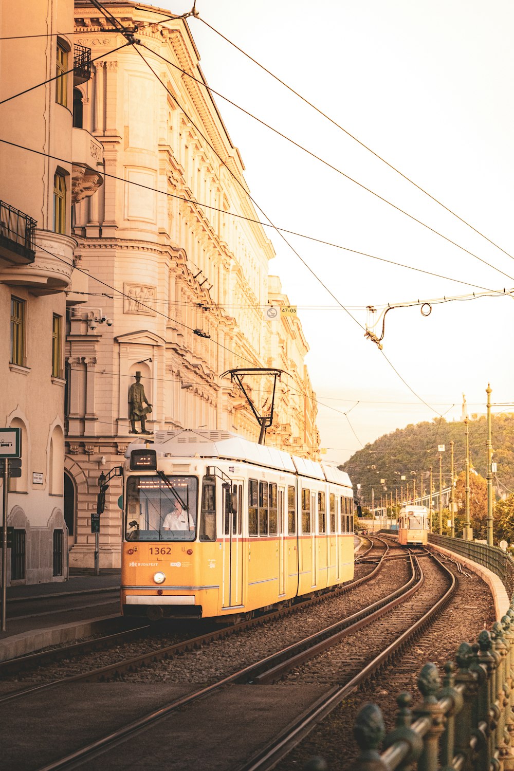 a yellow train traveling down train tracks next to a tall building