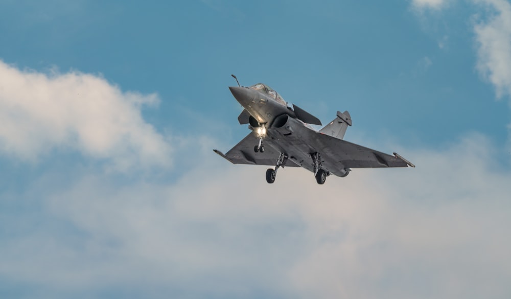 Un avión de combate volando a través de un cielo azul nublado