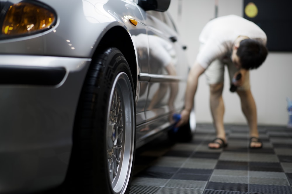 a man bending over next to a car on a checkered floor