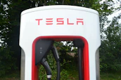 Close-up of electric vehicle charging station with green energy branding.