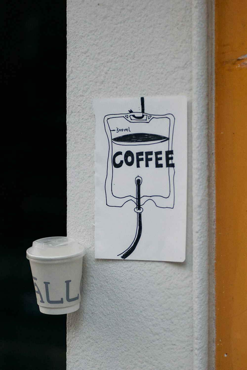 a cup of coffee sitting next to a sign on a wall