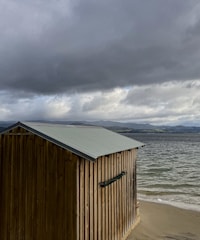 A rugged survivor crafting a wooden shelter under a stormy sky.